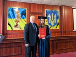 Роман Михайлович Савчук фотографується з випускницею, яка демонструє диплом.